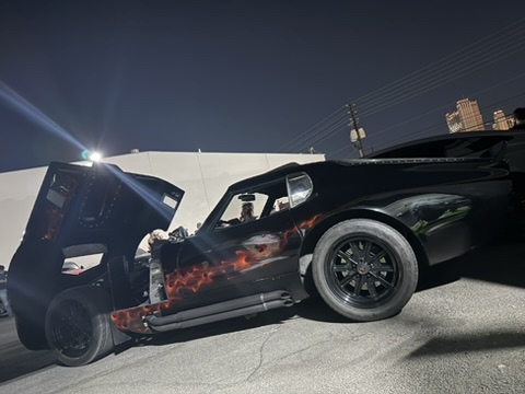 Low side view of the Factory Five Daytona replica with hood open at night