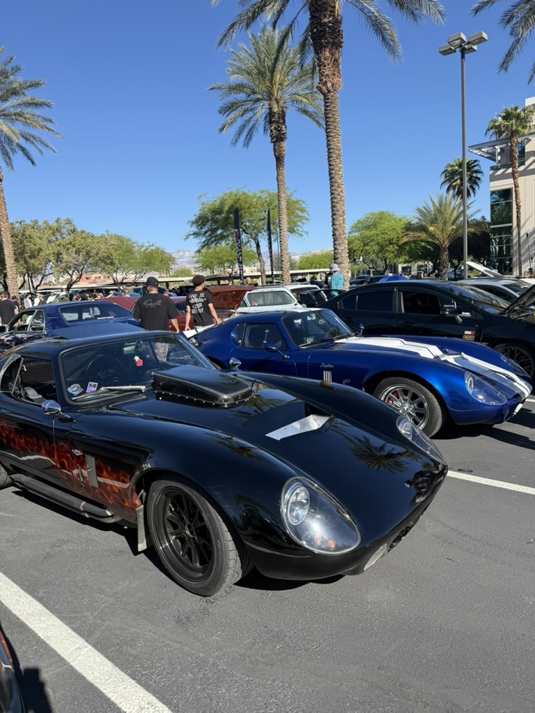 Factory Five Daytona replica parked beside a blue Daytona-style coupe at a car show